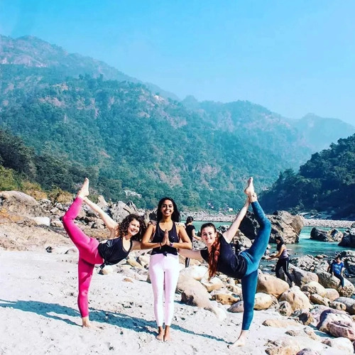 three yoga students practicing near river ganges